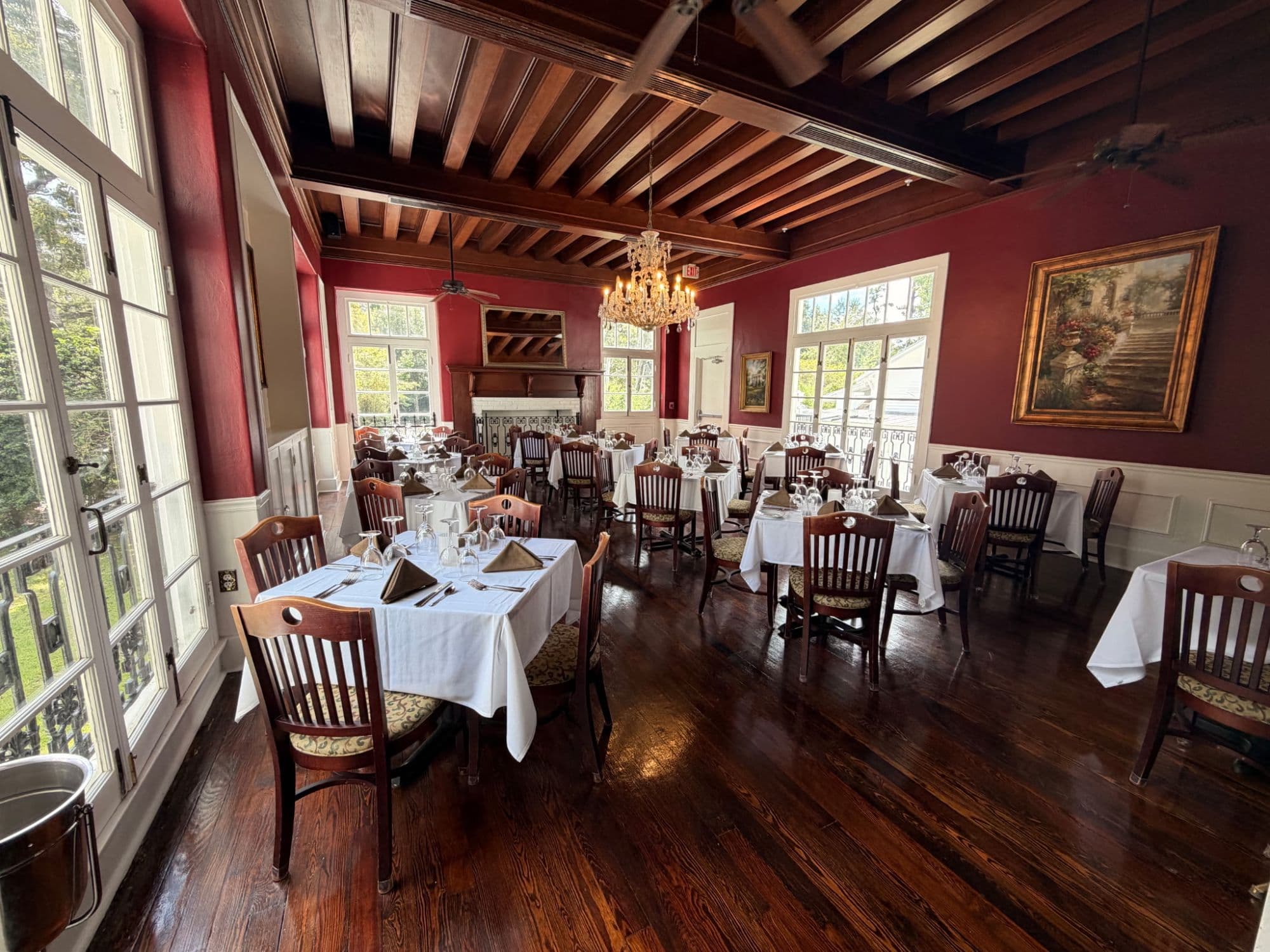 Red dining room with a beamed ceiling, crystal chandelier and French doors to the garden